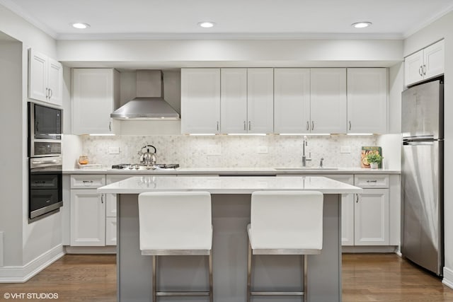 4428 N Racine Ave Unit Gn, Chicago, IL 60640 - kitchen with appliances with stainless steel finishes, wall chimney exhaust hood, a sink, light countertops, and ornamental molding