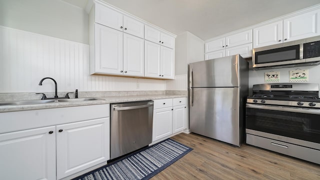325 Goodrich St, Belvidere, IL 61008 - kitchen featuring appliances with stainless steel finishes, a sink, light wood-style flooring, white cabinets, and wainscoting