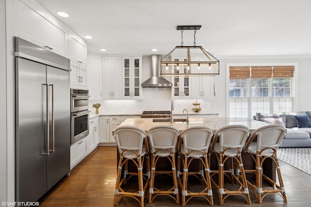 3414 N Bell Ave, Chicago, IL 60618 - kitchen featuring wall chimney range hood, appliances with stainless steel finishes, glass insert cabinets, white cabinetry, and backsplash