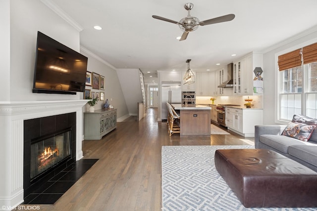 3414 N Bell Ave, Chicago, IL 60618 - living room featuring a ceiling fan, ornamental molding, a tiled fireplace, dark wood finished floors, and recessed lighting