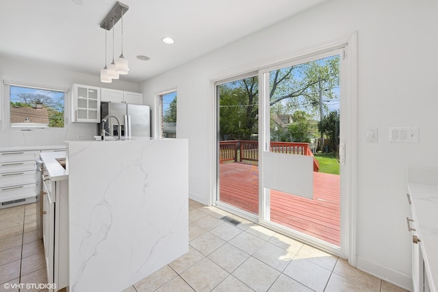 877 Hollywood Ave, Des Plaines, IL 60016 - kitchen featuring stainless steel refrigerator with ice dispenser, a kitchen island with sink, decorative light fixtures, light tile patterned floors, and white cabinetry