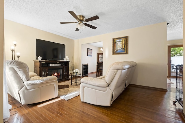 16203 Fox Ct, Orland Hills, IL 60487 - living area with a ceiling fan, hardwood / wood-style flooring, a textured ceiling, a glass covered fireplace, and baseboards