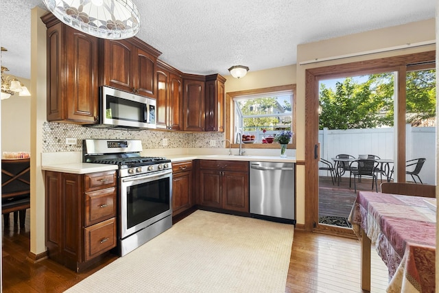 16203 Fox Ct, Orland Hills, IL 60487 - kitchen featuring appliances with stainless steel finishes, a textured ceiling, hardwood / wood-style flooring, light countertops, and tasteful backsplash