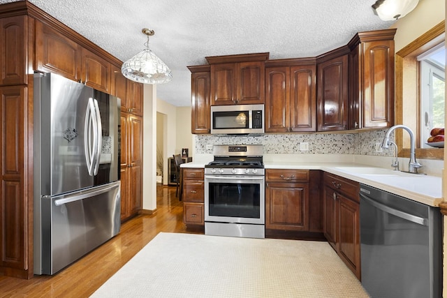 16203 Fox Ct, Orland Hills, IL 60487 - kitchen with stainless steel appliances, a sink, light countertops, light wood-type flooring, and a textured ceiling