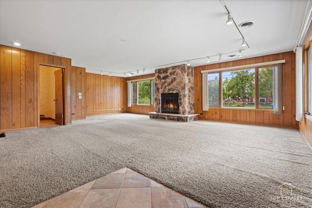 9258 Clancy Dr, Des Plaines, IL 60016 - unfurnished living room featuring track lighting, light carpet, a stone fireplace, and wooden walls