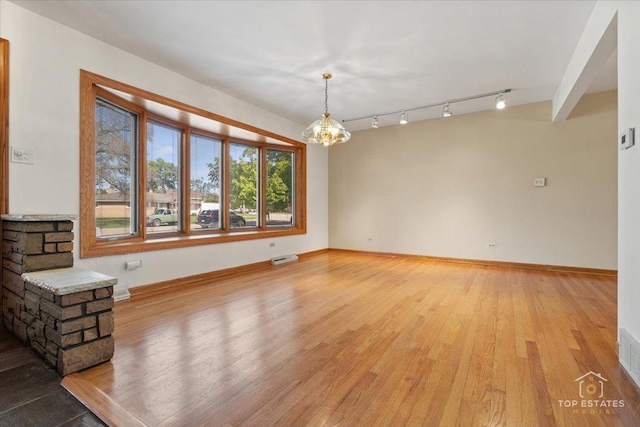 9258 Clancy Dr, Des Plaines, IL 60016 - unfurnished living room featuring wood finished floors, a chandelier, baseboards, and track lighting