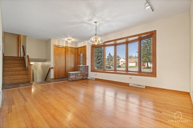 9258 Clancy Dr, Des Plaines, IL 60016 - unfurnished living room featuring light wood-style flooring, baseboards, a chandelier, and stairway