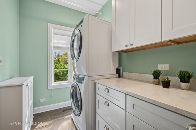 3118 Oliver Ln, Northbrook, IL 60062 - laundry area with cabinet space, stacked washer and clothes dryer, wood finished floors, and baseboards