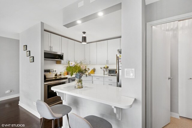 1636 N Wells St Unit 1107, Chicago, IL 60614 - kitchen featuring stainless steel appliances, a kitchen bar, baseboards, a peninsula, and light countertops