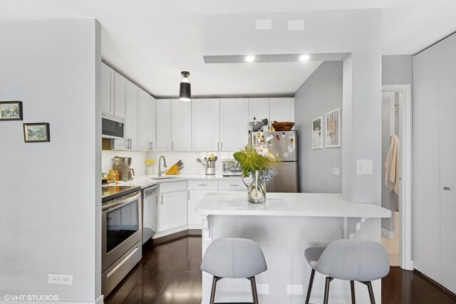 1636 N Wells St Unit 1107, Chicago, IL 60614 - kitchen featuring appliances with stainless steel finishes, dark wood-style floors, a kitchen breakfast bar, white cabinetry, and light countertops