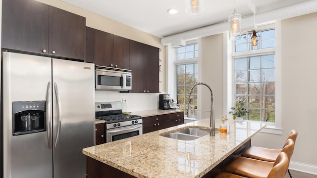 636 N Racine Ave Unit 2N, Chicago, IL 60642 - kitchen featuring stainless steel appliances, a sink, a breakfast bar area, a kitchen island with sink, and dark brown cabinetry