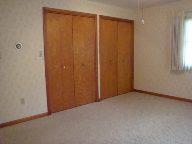 423 W Garfield Ave, Cissna Park, IL 60924 - unfurnished bedroom with two closets, carpet, and wallpapered walls