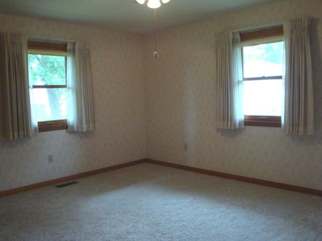 423 W Garfield Ave, Cissna Park, IL 60924 - empty room with carpet floors, wallpapered walls, ceiling fan, and baseboards