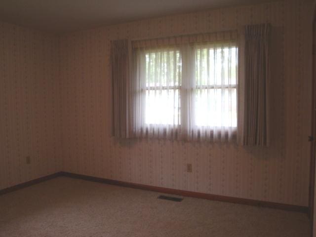 423 W Garfield Ave, Cissna Park, IL 60924 - spare room with plenty of natural light, wallpapered walls, and baseboards