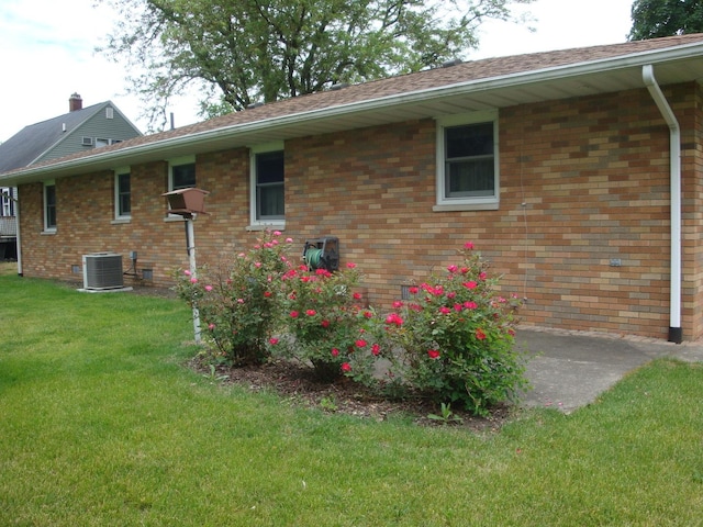 423 W Garfield Ave, Cissna Park, IL 60924 - view of property exterior featuring central AC, a lawn, brick siding, and a patio