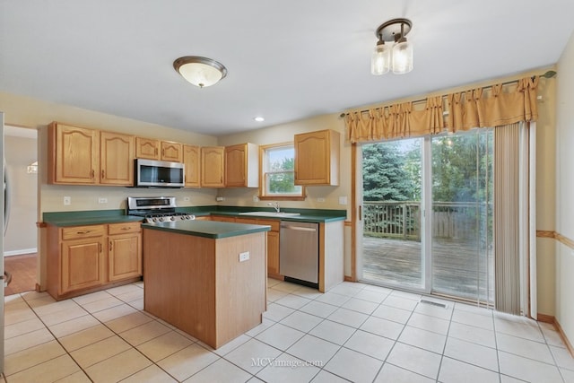 2853 Coastal Dr, Aurora, IL 60503 - kitchen with appliances with stainless steel finishes, dark countertops, a sink, a kitchen island, and light tile patterned floors