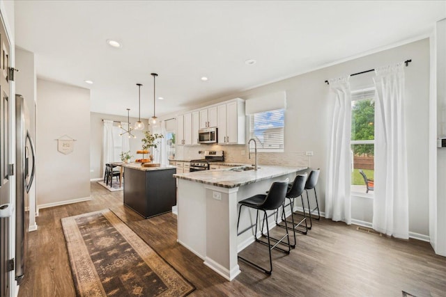 26143 S White Oak Trl, Channahon, IL 60410 - kitchen featuring stainless steel appliances, a sink, a peninsula, a kitchen island, and white cabinetry
