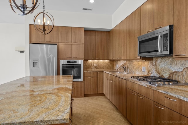 1322 N Clybourn Ave Unit 4S, Chicago, IL 60610 - kitchen with stainless steel appliances, a sink, light stone countertops, backsplash, and a chandelier
