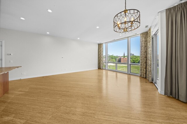 1322 N Clybourn Ave Unit 4S, Chicago, IL 60610 - unfurnished living room featuring a chandelier, a wall of windows, recessed lighting, light wood-style flooring, and baseboards