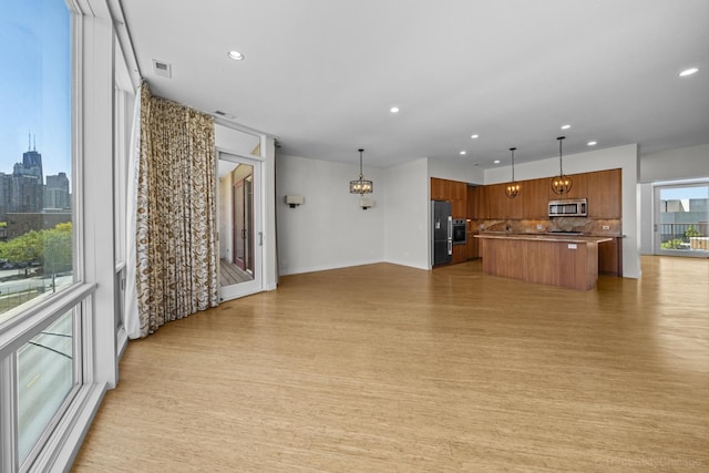 1322 N Clybourn Ave Unit 4S, Chicago, IL 60610 - kitchen featuring appliances with stainless steel finishes, open floor plan, brown cabinets, a kitchen island, and decorative backsplash