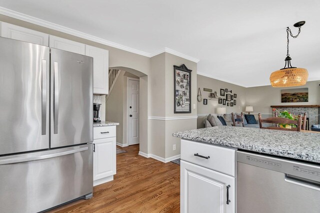 633 Salem Cir, Oswego, IL 60543 - kitchen featuring stainless steel appliances, light wood finished floors, baseboards, arched walkways, and white cabinetry