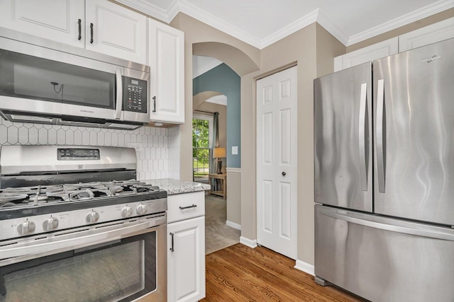 633 Salem Cir, Oswego, IL 60543 - kitchen featuring stainless steel appliances, crown molding, wood finished floors, arched walkways, and white cabinets