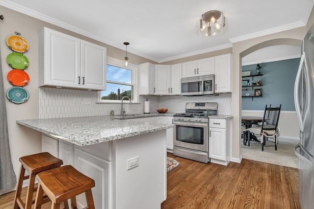 633 Salem Cir, Oswego, IL 60543 - kitchen featuring appliances with stainless steel finishes, a kitchen bar, a peninsula, white cabinets, and crown molding