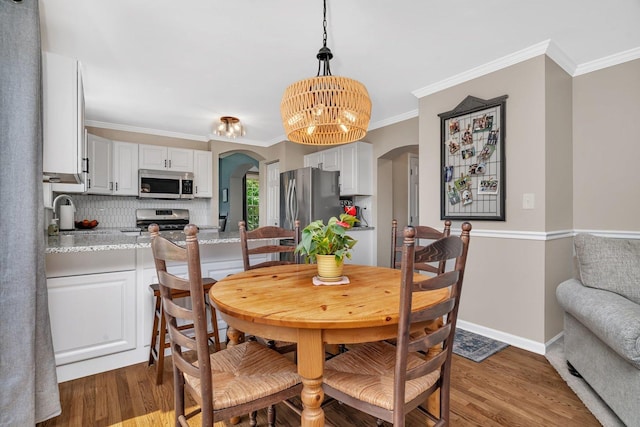 633 Salem Cir, Oswego, IL 60543 - dining room with arched walkways, wood finished floors, a chandelier, ornamental molding, and baseboards