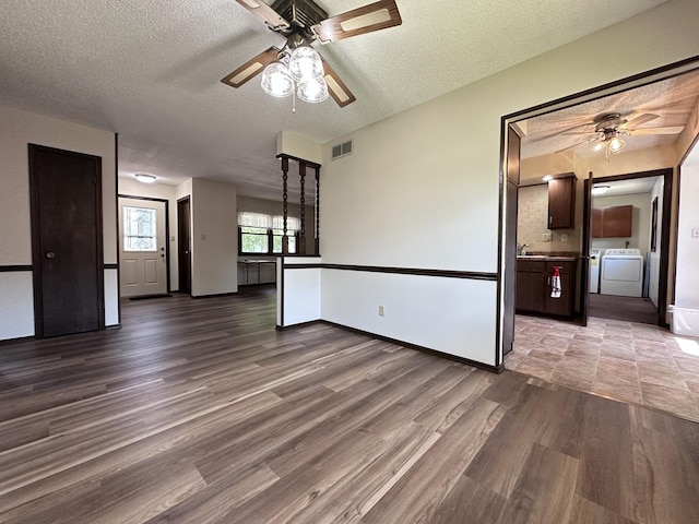 600 E 7th St, Rock Falls, IL 61071 - unfurnished living room featuring a ceiling fan, wood finished floors, washing machine and dryer, a textured ceiling, and baseboards