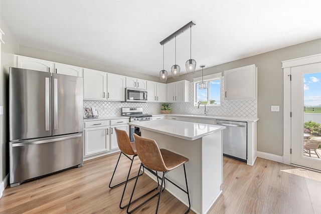 15905 Rolland Dr, Manhattan, IL 60442 - kitchen featuring stainless steel appliances, light wood finished floors, white cabinetry, and a breakfast bar