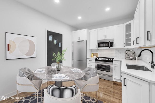 8127 S Jeffery Blvd, Chicago, IL 60617 - kitchen with stainless steel appliances, a sink, wood finished floors, white cabinetry, and tasteful backsplash