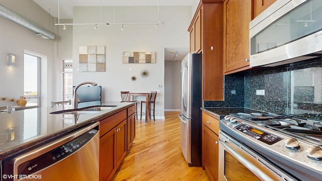 2025 S Indiana Ave Unit 503, Chicago, IL 60616 - kitchen featuring appliances with stainless steel finishes, brown cabinetry, a sink, light wood-style flooring, and decorative backsplash