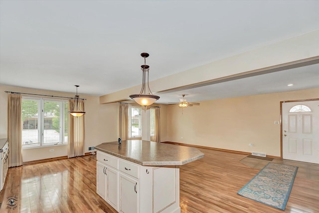 16560 Currant Ave, Tinley Park, IL 60487 - kitchen with baseboards, white cabinets, a center island, light wood-style floors, and hanging light fixtures
