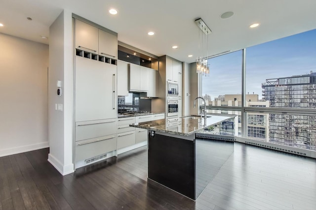 110 W Superior St Unit 1703, Chicago, IL 60654 - kitchen featuring a sink, appliances with stainless steel finishes, dark stone countertops, dark wood-type flooring, and hanging light fixtures