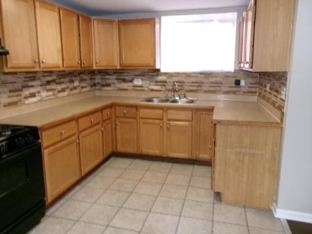 kitchen featuring a sink, black range with gas cooktop, decorative backsplash, and light countertops