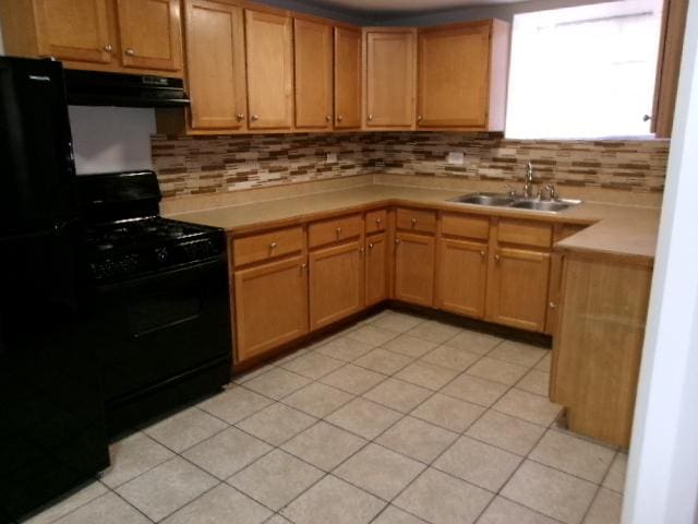 kitchen with ventilation hood, black appliances, decorative backsplash, and a sink