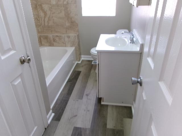 full bathroom featuring vanity, toilet, wood finished floors, and baseboards
