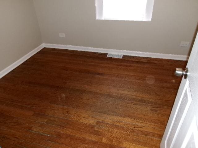 unfurnished room with dark wood-style flooring and baseboards