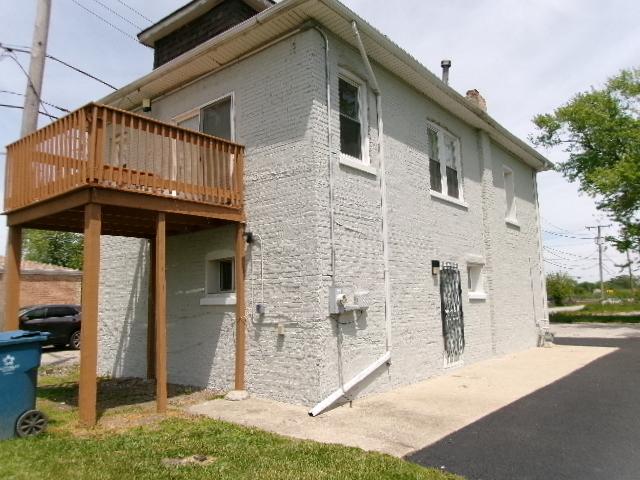 view of property exterior with a wooden deck, a chimney, and brick siding