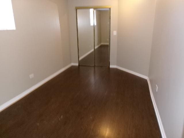 unfurnished room with dark wood-type flooring and baseboards