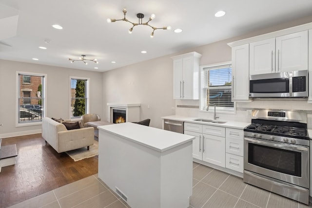 2415 W Washburne Ave, Chicago, IL 60608 - kitchen with appliances with stainless steel finishes, a sink, plenty of natural light, a warm lit fireplace, and recessed lighting