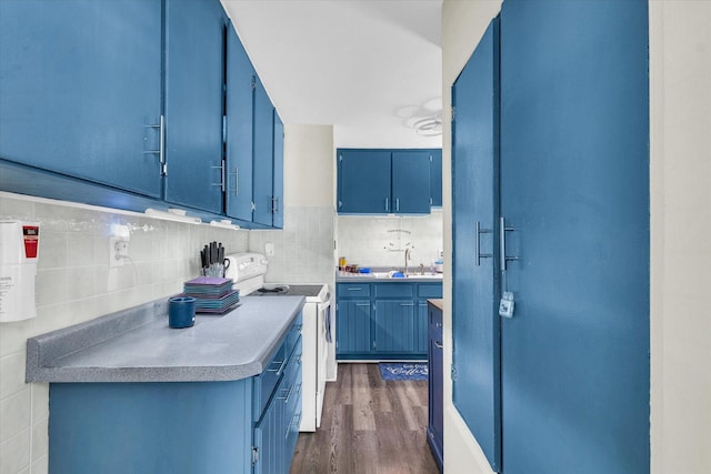 308 W Spruce St, Paxton, IL 60957 - kitchen with white electric range oven, blue cabinetry, dark wood-style floors, tasteful backsplash, and light countertops