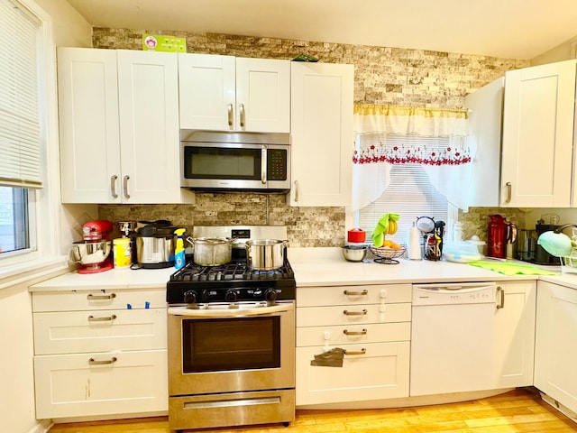 6228 N Artesian Ave, Chicago, IL 60659 - kitchen featuring stainless steel appliances, light countertops, backsplash, light wood-style flooring, and white cabinets