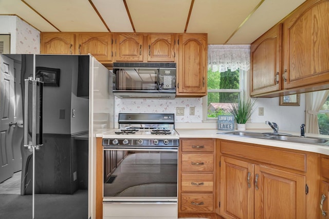 75 Largemouth Ln, Wilmington, IL 60481 - kitchen with black microwave, white range with gas cooktop, a sink, light countertops, and wallpapered walls