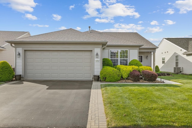 12183 Wildflower Ln, Huntley, IL 60142 - view of front of house with asphalt driveway, central AC unit, a front lawn, a garage, and a shingled roof