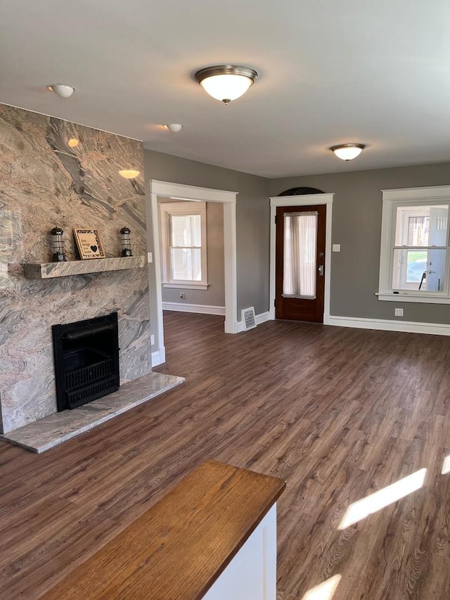407 N William St, Joliet, IL 60435 - unfurnished living room featuring baseboards, a fireplace, healthy amount of natural light, and dark wood-style flooring