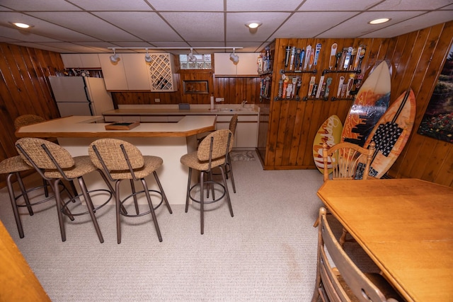 405 Farmington Ave, Joliet, IL 60435 - kitchen with freestanding refrigerator, wooden walls, light carpet, a paneled ceiling, and a breakfast bar