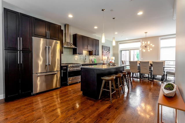 2823 N Oakley Ave Unit K, Chicago, IL 60618 - kitchen featuring high quality appliances, wall chimney range hood, a center island, a breakfast bar area, and dark wood-style floors
