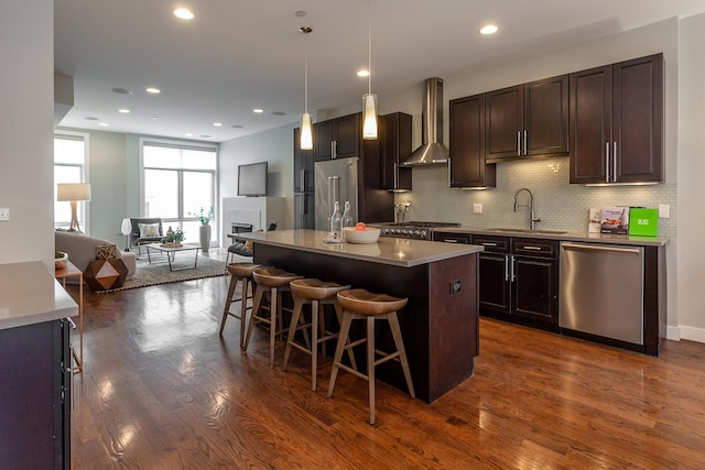 2823 N Oakley Ave Unit K, Chicago, IL 60618 - kitchen featuring stainless steel appliances, wall chimney range hood, a sink, a kitchen breakfast bar, and tasteful backsplash