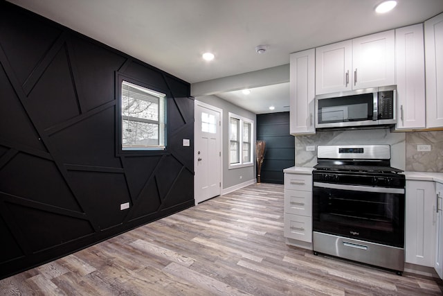 34 W 142nd St, Harvey, IL 60426 - kitchen featuring stainless steel appliances, light countertops, decorative backsplash, white cabinets, and light wood-style floors